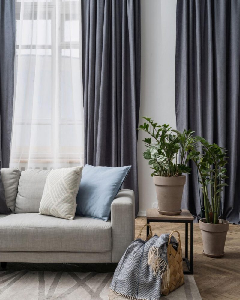 Concept of vintage objects and antique furniture. Cushions on retro style couch close to old decor in apartment. Vertical view of flooring lamp near houseplant in flower pot stand at living room